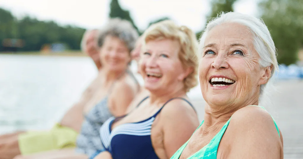 3 retired ladies very happy and smiling poolside.