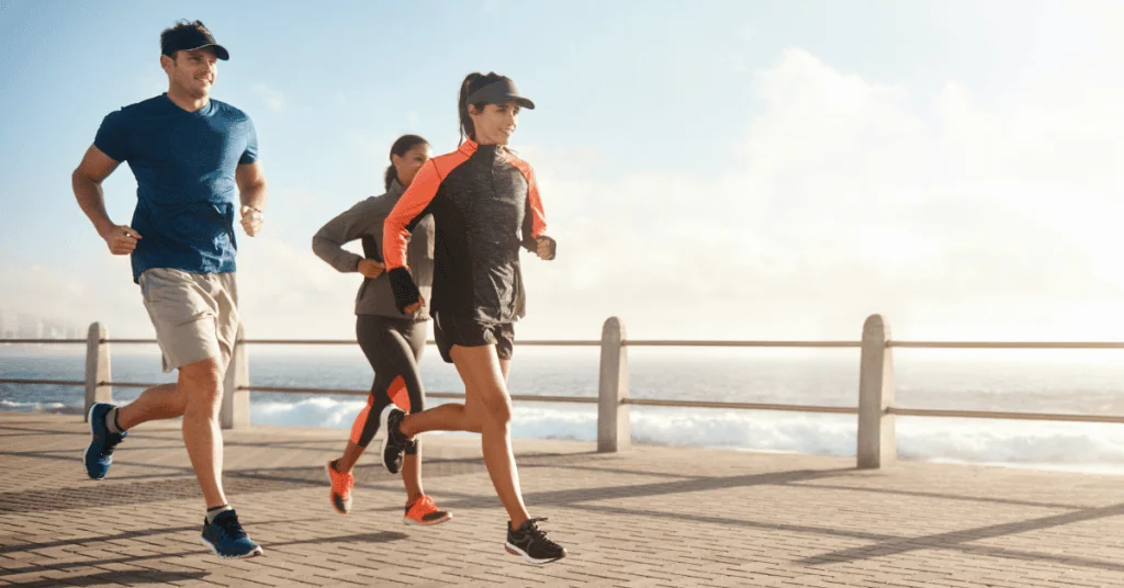 Three people jogging by a beach.