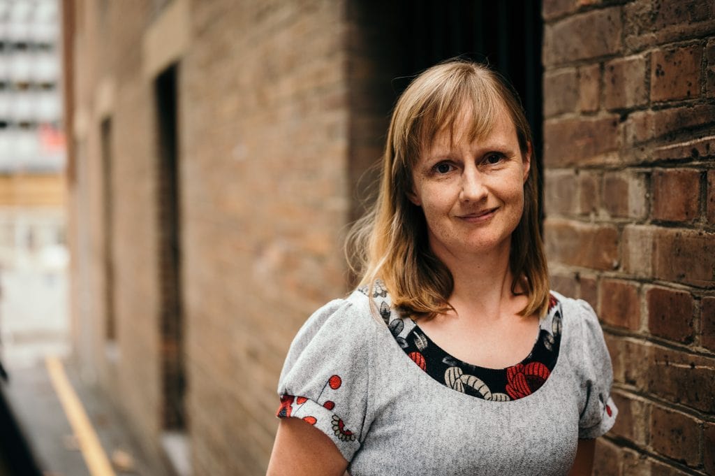 Portrait of Amanda against brick wall. 