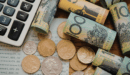 Cash on table with calculator and list.